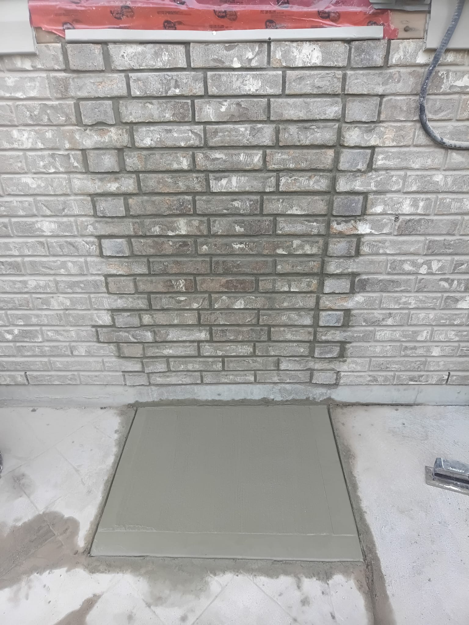 Rebuilt brick wall with new concrete pad after repair