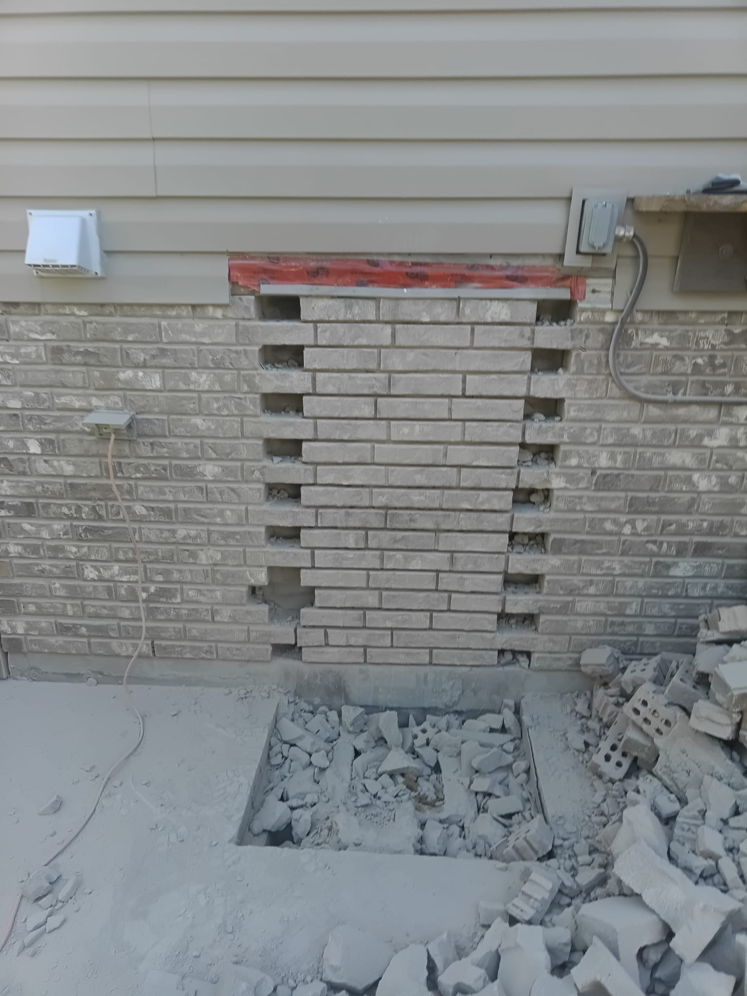 Brick wall opened up with surrounding debris before repair