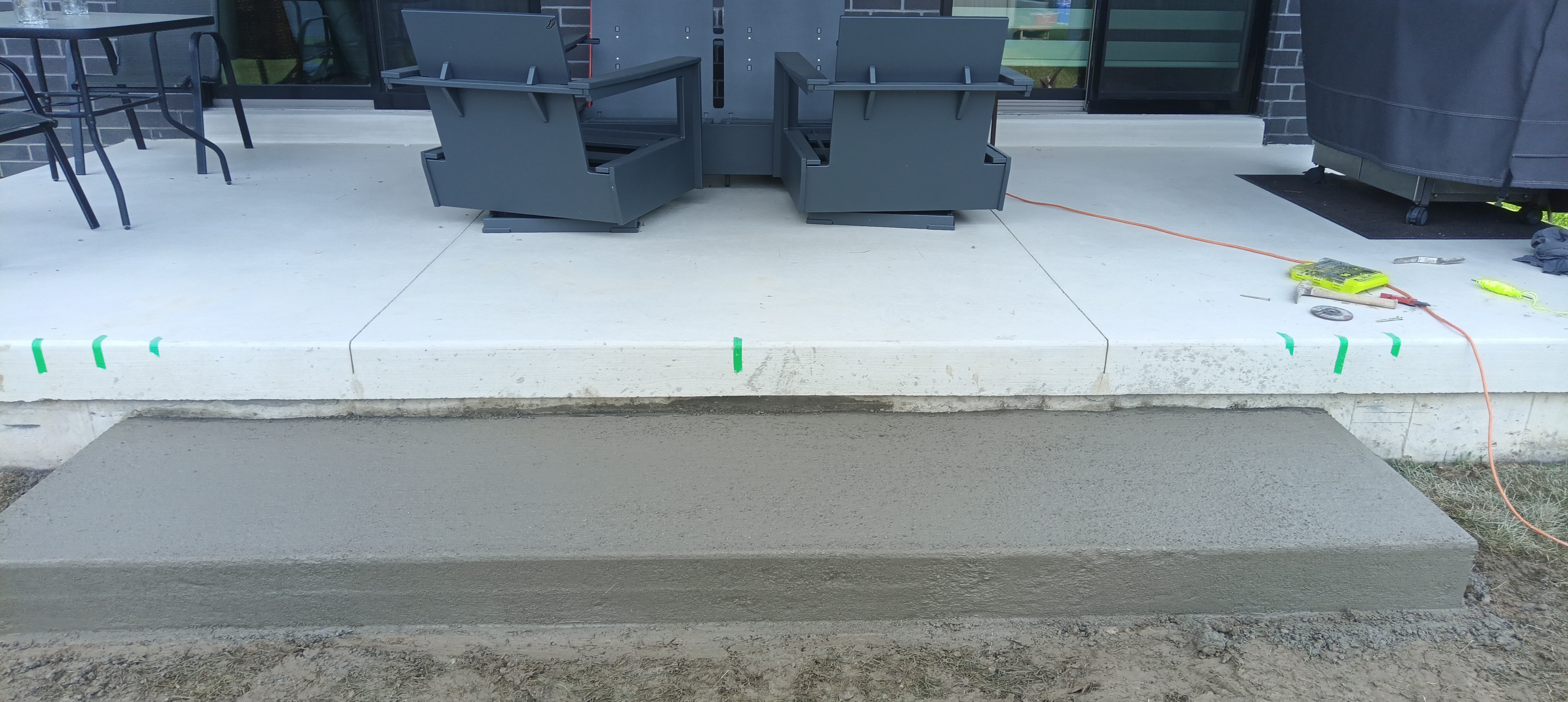 Newly poured concrete landing step running the width of the patio